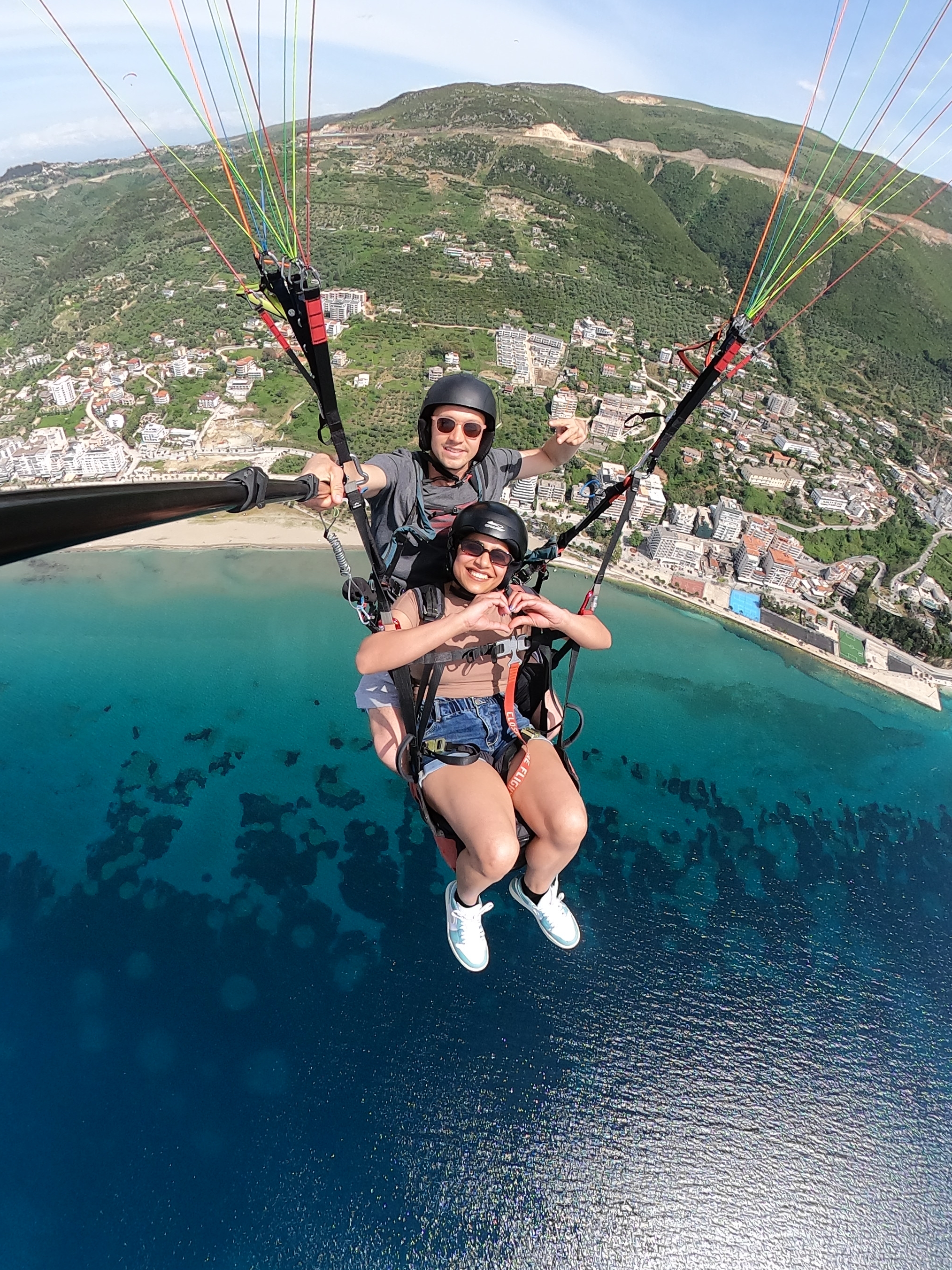 Tandem paragliding with heart gesture above the Ionian coast near Vlora