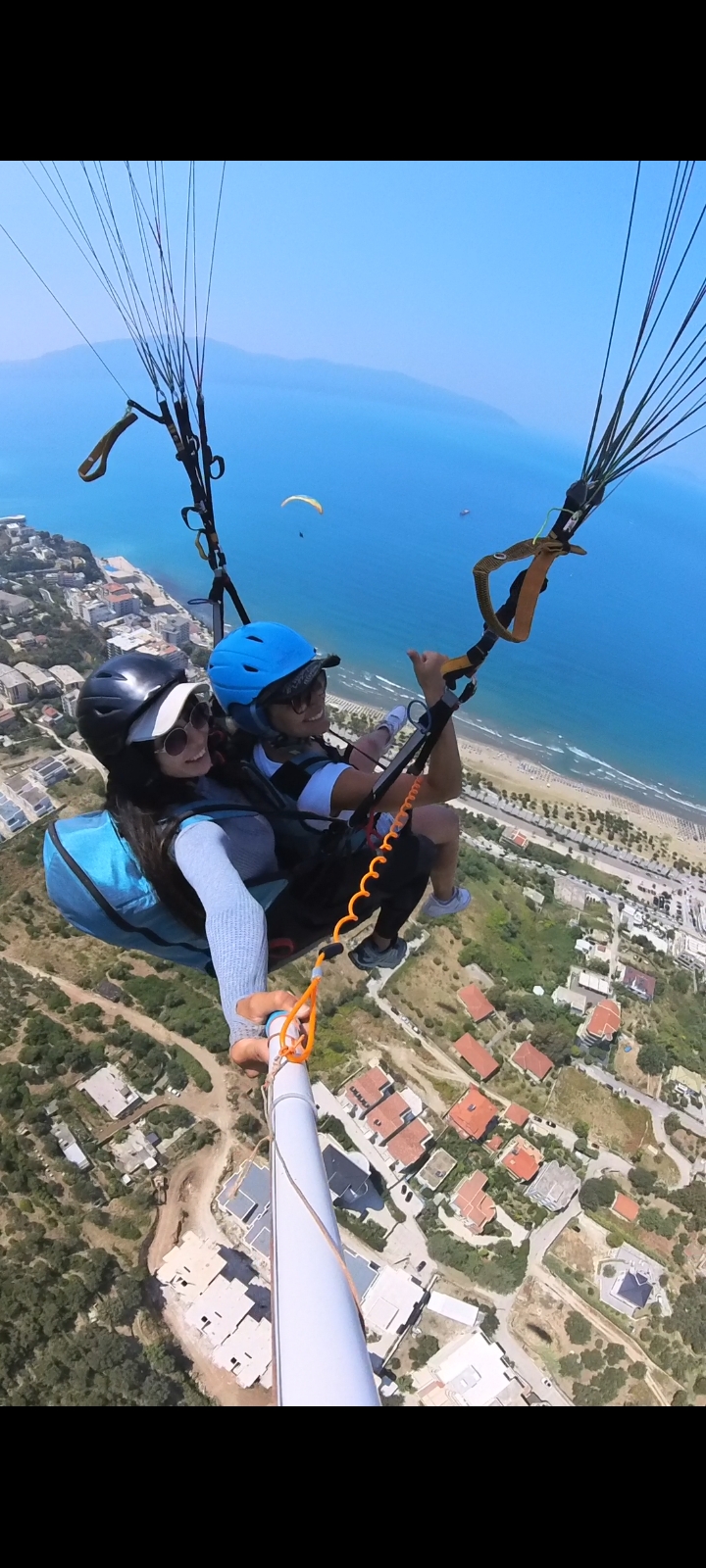 Tandem flight above the beach with clear blue sea in the background